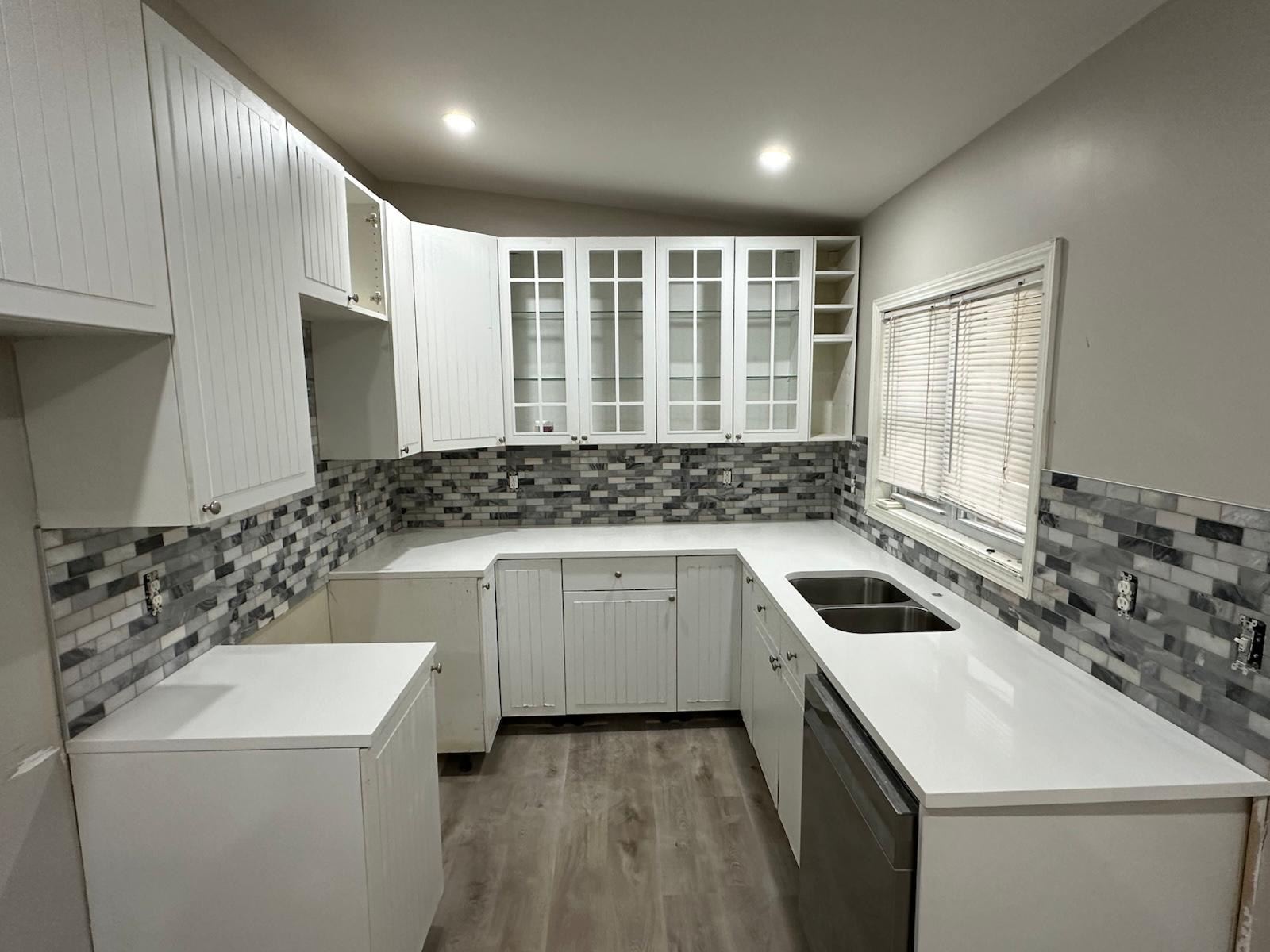 Full kitchen with white cabinets, mosaic backsplash, and quartz countertops
