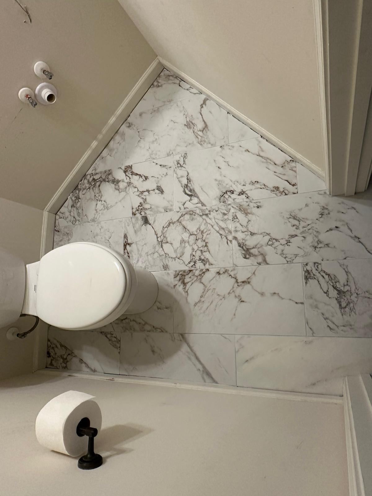 Marble-look tile accent wall in an angled ceiling nook